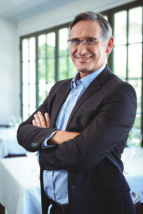 Smiling businessman posing with crossed arms in a restaurant