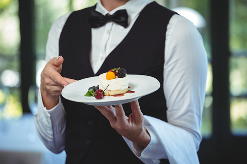 Waitress holding a plate with dessert in a restaurant