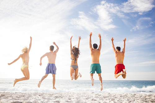 Happy friends jumping together on the beach