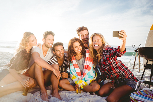 Happy friends taking selfie with smartphone on the beach
