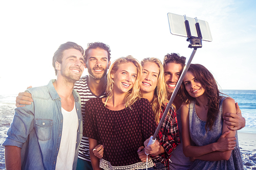 Happy friends taking selfie with selfie stick on the beach