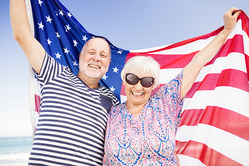 Senior couple holding american flag together on beach
