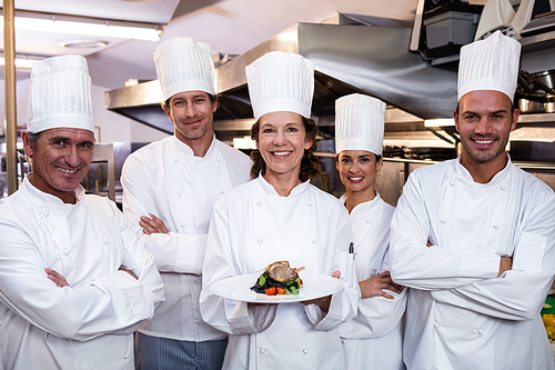 Team of chefs in the kitchen with one presenting a dish