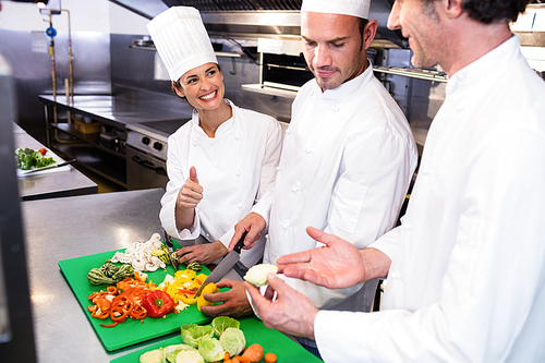 head-chef-teaching-his-colleagues-how-to-slice-vegetables-in