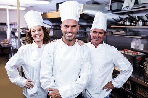 Group of happy chefs in uniform smiling at the camera in a kitchen