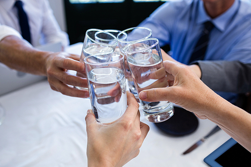 Group of businesspeople toasting glass of water during business meeting in restaurant
