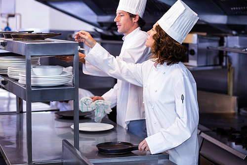 Two chefs working at order station in a restaurant kitchen