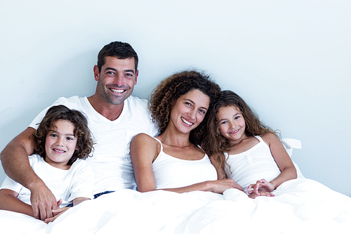 Portrait of a family sitting together on bed at home