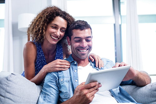 Young couple using digital tablet on sofa at home