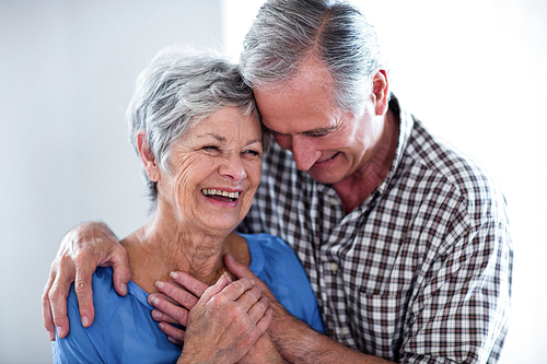 Happy senior couple smiling while embracing at home