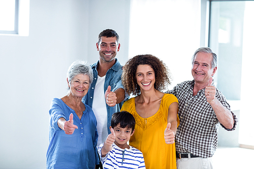 Portrait of happy family showing their thumbs up at home