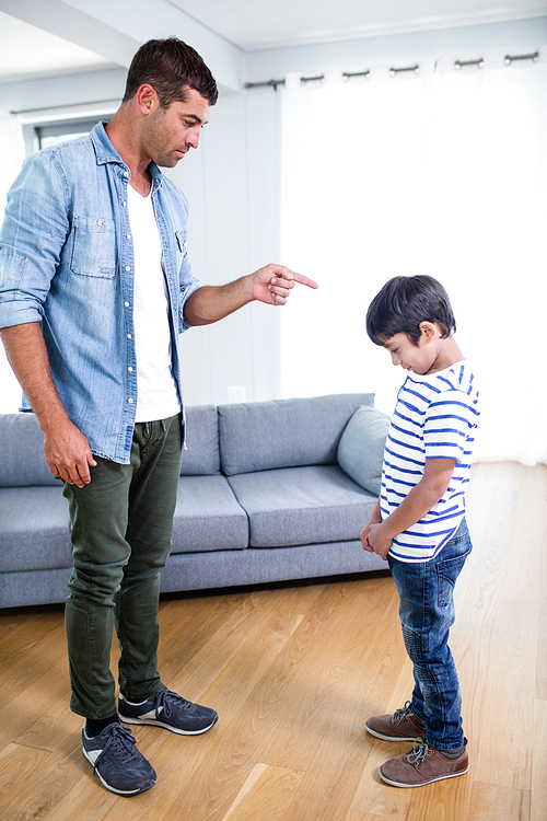 Angry father scolding his son in living room at home