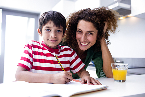 Happy mother helping son with homework in kitchen