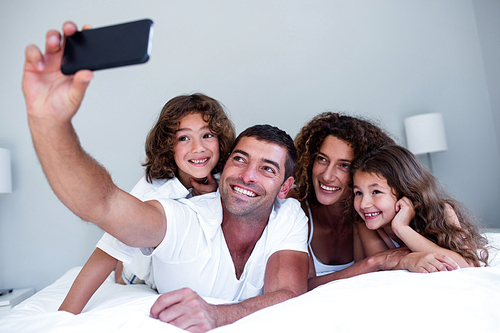 Happy family taking a selfie on bed in bedroom
