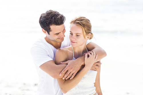 Young couple embracing each other on the beach on a sunny day