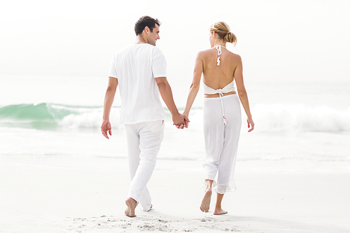 Rear view of couple walking on the beach on a sunny day