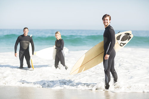 Portrait of surfer friends with surfboard standing on the beach on a sunny day