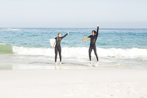 Couple with surfboard standing on the beach on a sunny day