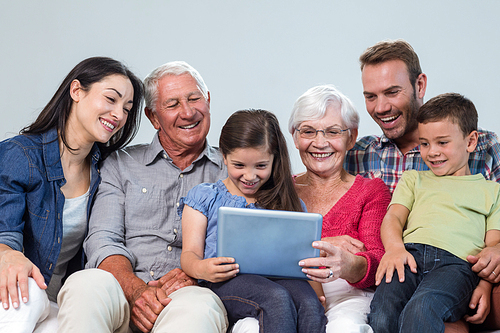 Happy family sitting on sofa using a digital tablet in living room