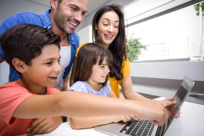 Happy family interacting using laptop in their living room