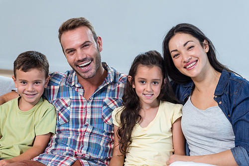 Portrait of family sitting on sofa and smiling in living room