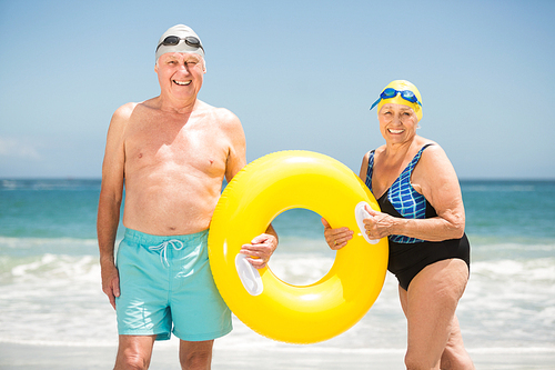 Senior couple with swimming ring at the beach on a sunny day