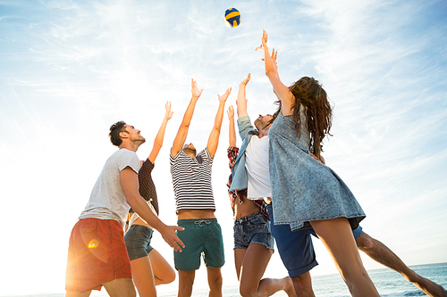 Friends trying to catch volley ball on a sunny day