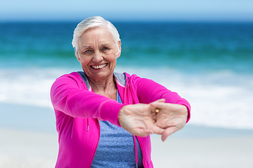 Thoughtful mature woman outstretching her arms on the beach