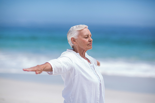 Side view of mature woman posing with outstretched arms at the beach