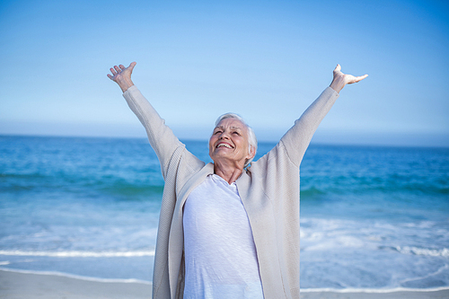 Beautiful mature woman outstretching arms at the beach