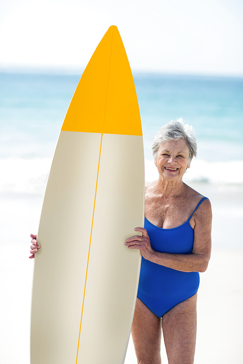 Mature woman posing with a surfboard at the beach