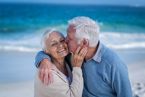 Senior couple embracing and kissing at the beach