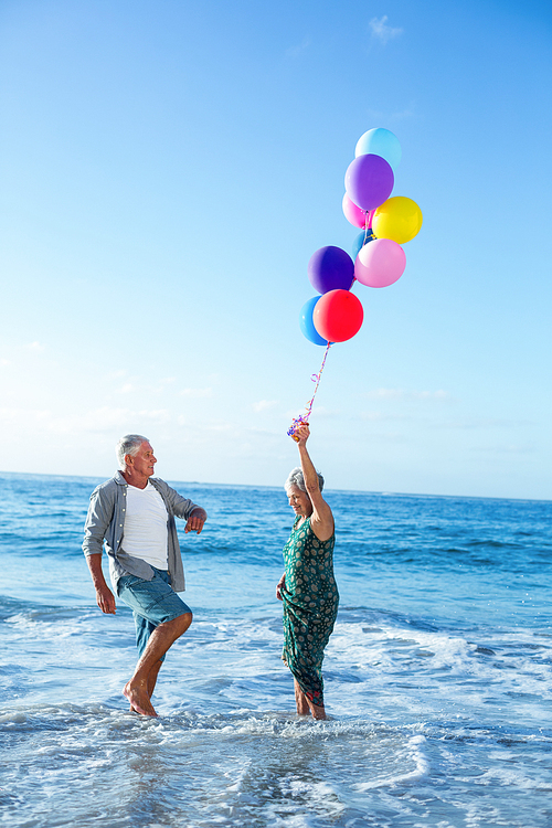 Senior couple holding balloons at the beach