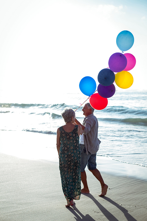 Senior couple holding balloons at the beach