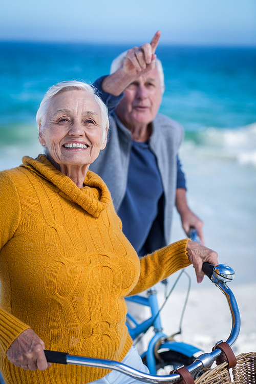 Senior couple with bikes pointing at the beach