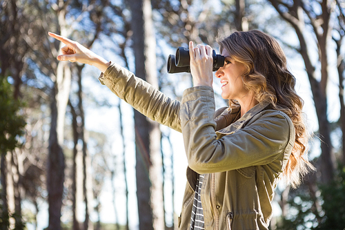 Woman using binoculars in the forest
