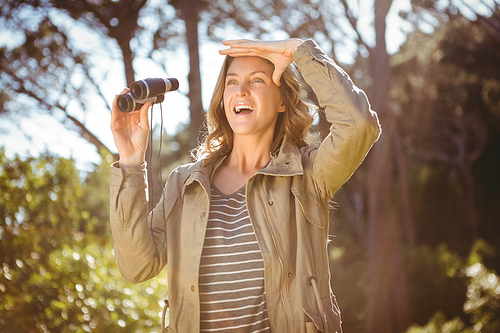 Smiling woman holding binoculars in the countryside