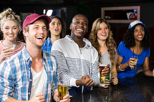 Happy friends watching sport in a bar