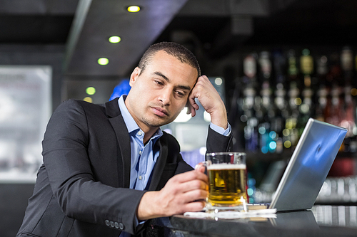 Worried businessman drinking a beer at a bar