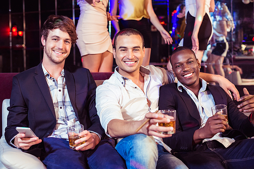 Happy friends holding glass of alcohol in a club