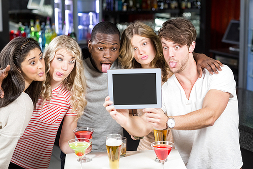 Friends taking selfie with a tablet in a bar