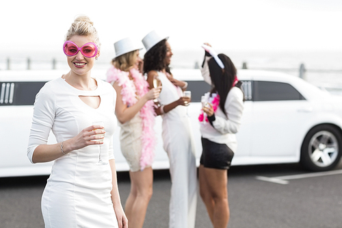 Frivolous women drinking champagne next to a limousine on a night out