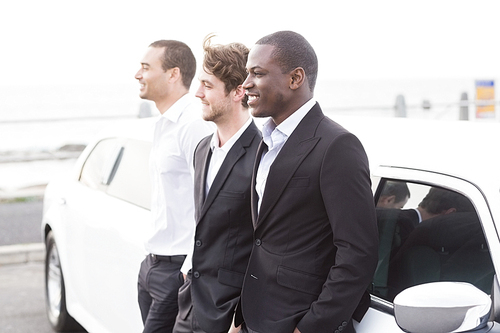 Well dressed men posing leaning on a limousine on a night out