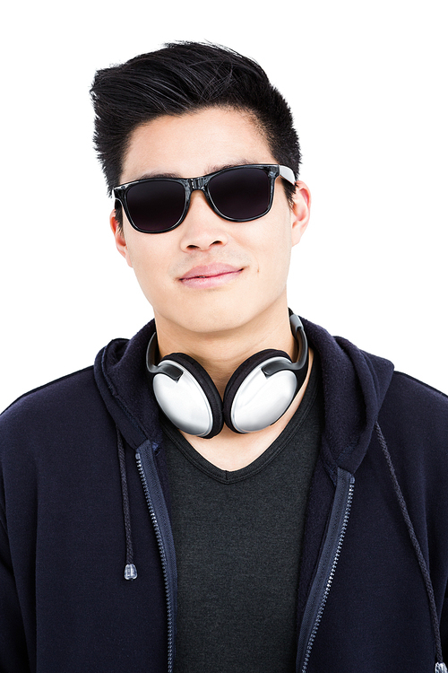 Close-up of young man in sunglasses and headphones on white background