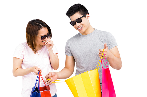 Young couple holding shopping bags and smiling on white background