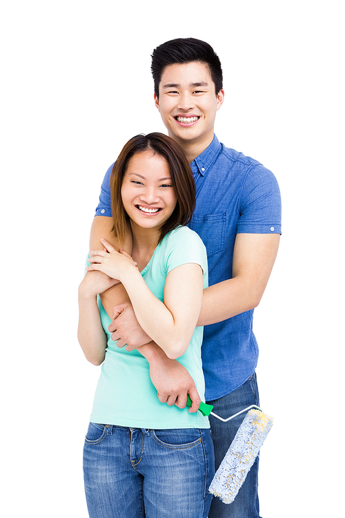 Young couple standing with paint roller on white background