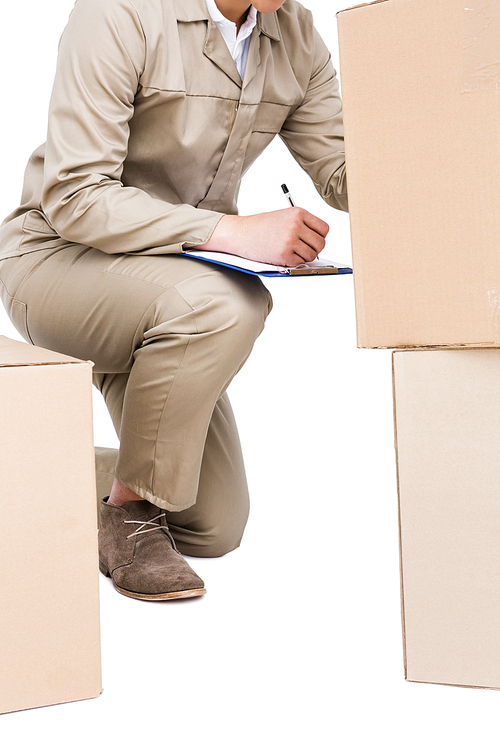 Delivery man making notes and counting cardboard boxes on white background