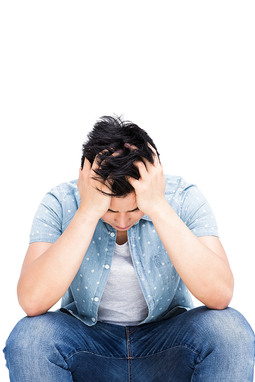 Frustrated man sitting with his hands on head on white background