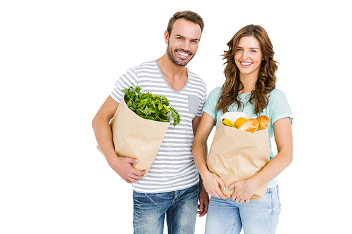 Portrait of happy young couple holding bag of vegetables on white background