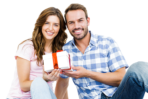 Portrait of happy young couple holding gift on white background